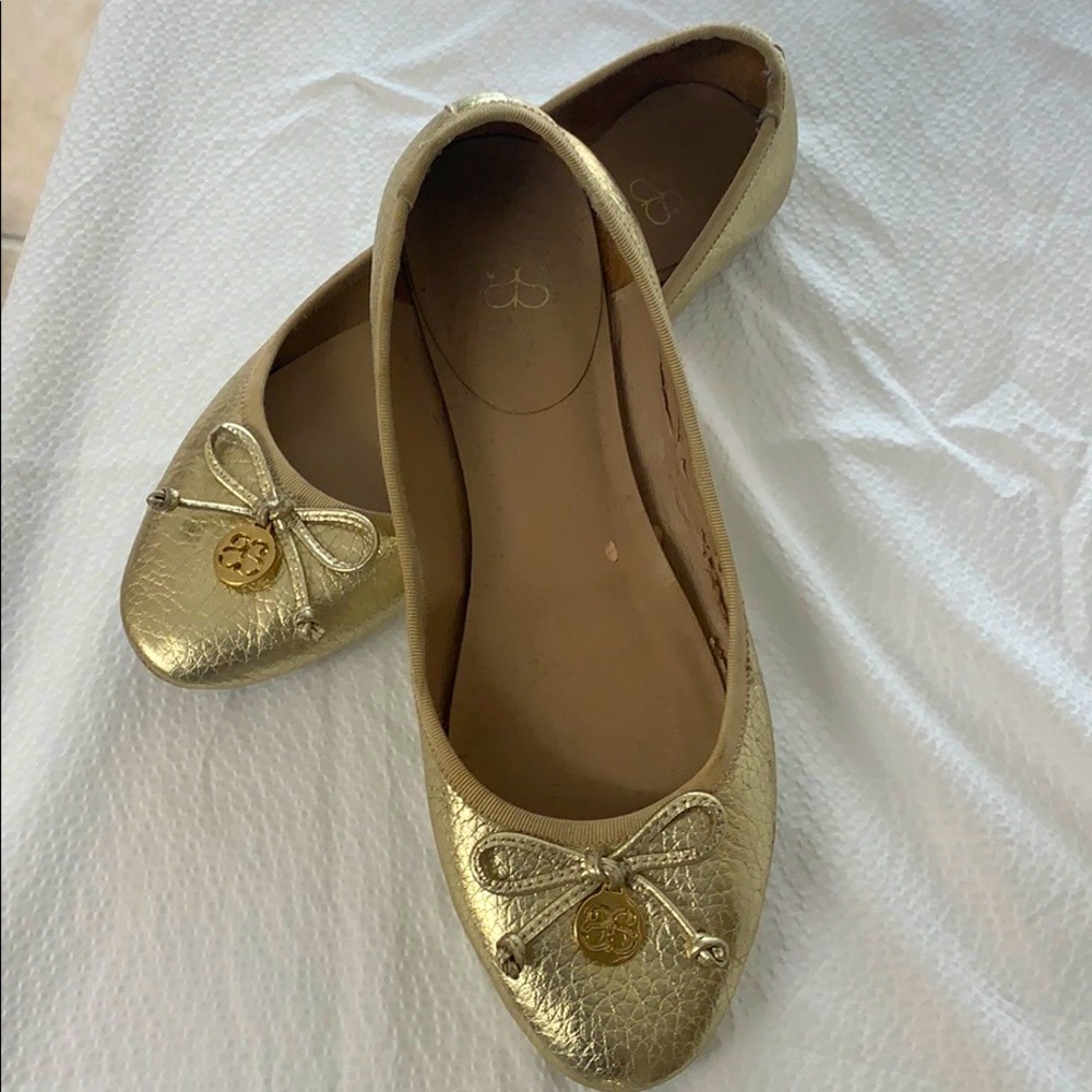 Gold flat shoes with gold tag and bow.